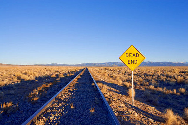 Railroads desert mountains off in the distance dead end sign